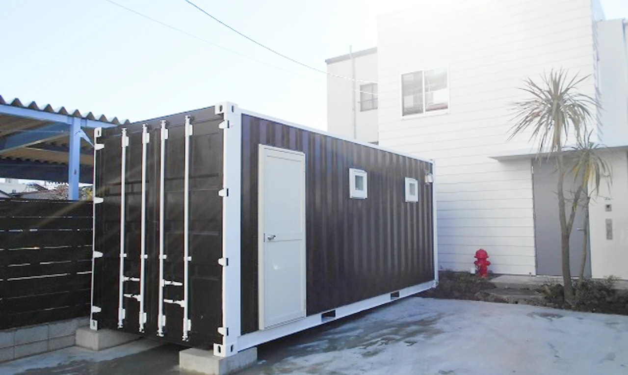 住宅の敷地内に設置された黒いコンテナ型の小型建物
