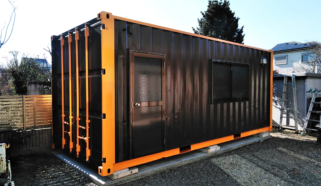 作業員がコンテナの外壁に塗装を施している様子